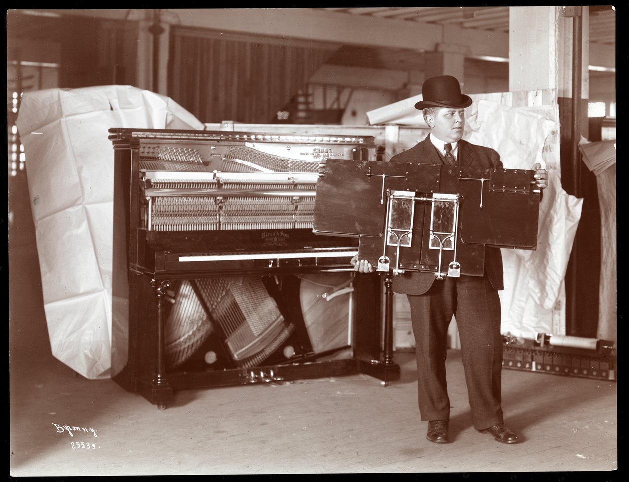 Klavír od Ricca and Son Piano Co. s mužem vedle sebe držícím část klavírních děl, 1907 (stříbrný želatinový tisk) od Byron Company