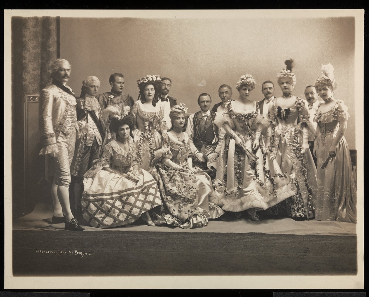 Skupinový portrét Edmunda Lincolna Bayliese (sedící uprostřed) a Ruth Payson (paní E.L.) Bayliesové (stojící třetí zprava) na plese Jamese Hazena Hydea, New York, 31. ledna 1905 (stříbrná želatina). od Byron Company