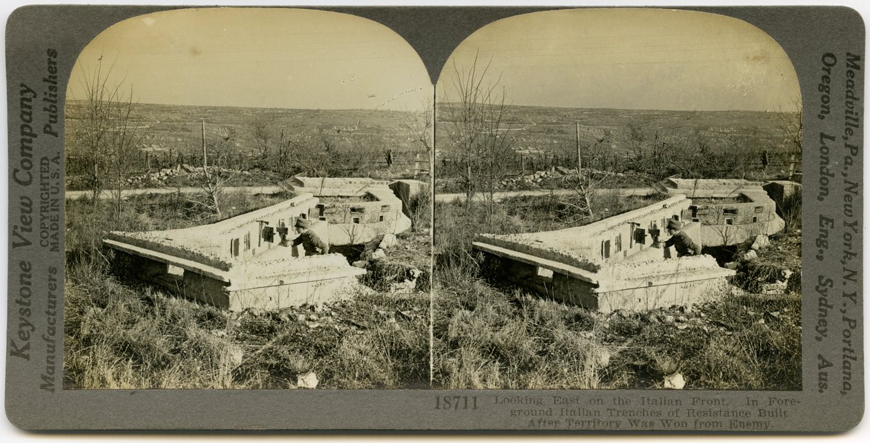 Horizontální, sépiová stereokarta zobrazující uniformovaného muže stojícího za sadou betonových zákopů v otevřeném poli. Keystone Stereograph číslo 18711. Název zní od Keystone View Company