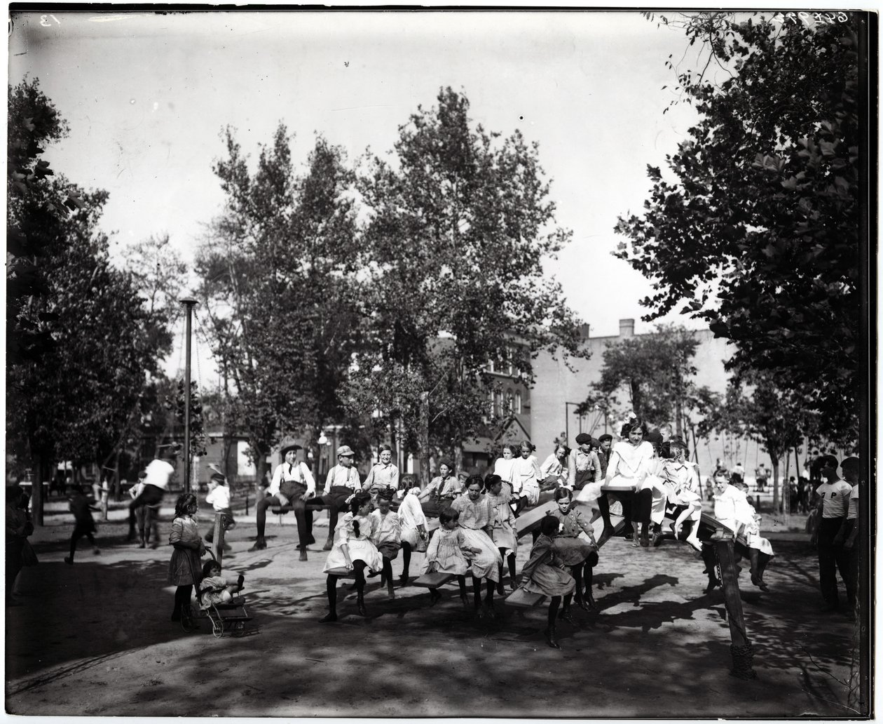 Horizontální, černobílá fotografie zobrazující děti hrající si na houpačkách v neznámém parku od Unknown