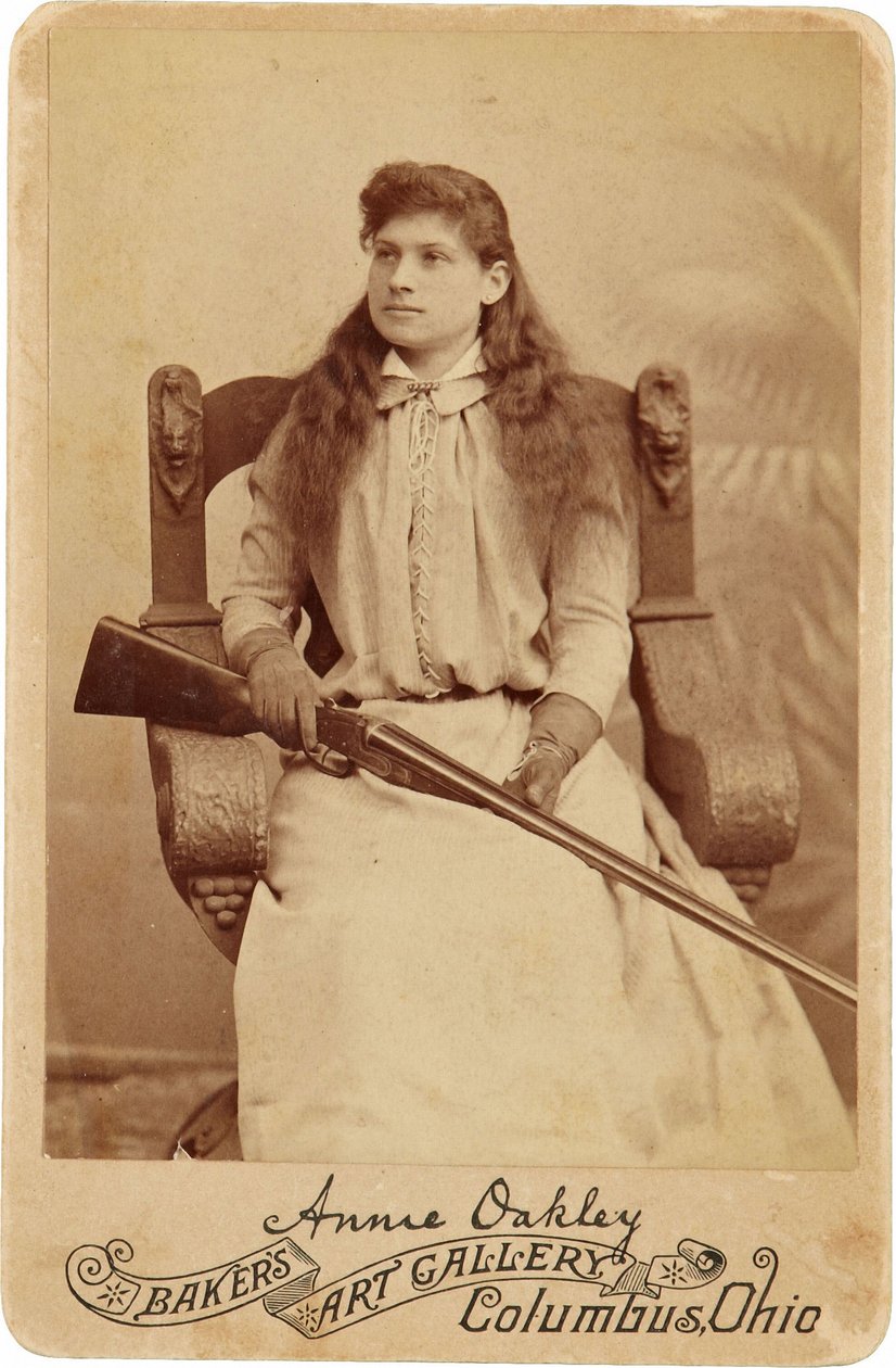Annie Oakley: Annie Oakley:. Legendární ostrostřelec zde sedí poněkud zdrženlivě v masivním křesle v renesančním stylu a brokovnici spočívající v jejím klíně. Její jemné ženské rysy a vlající vlasy Belie Her Rugged Outdoors Obrázek ©Buyenlarge/UIG/Leemage od American Photographer