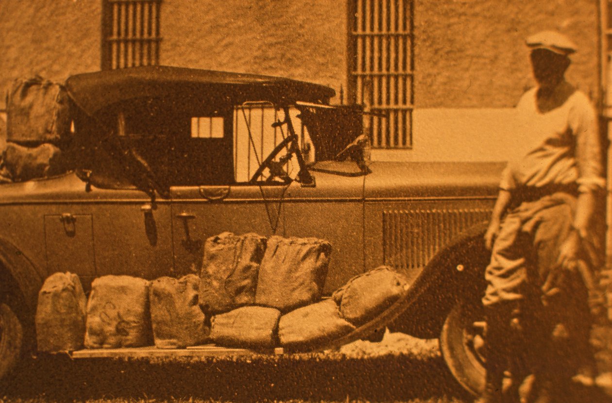 Šunky - balíčky po šesti lahvích ve slámě a papír na vycpávku do pytloviny, v době prohibice (sépiové foto) od American Photographer