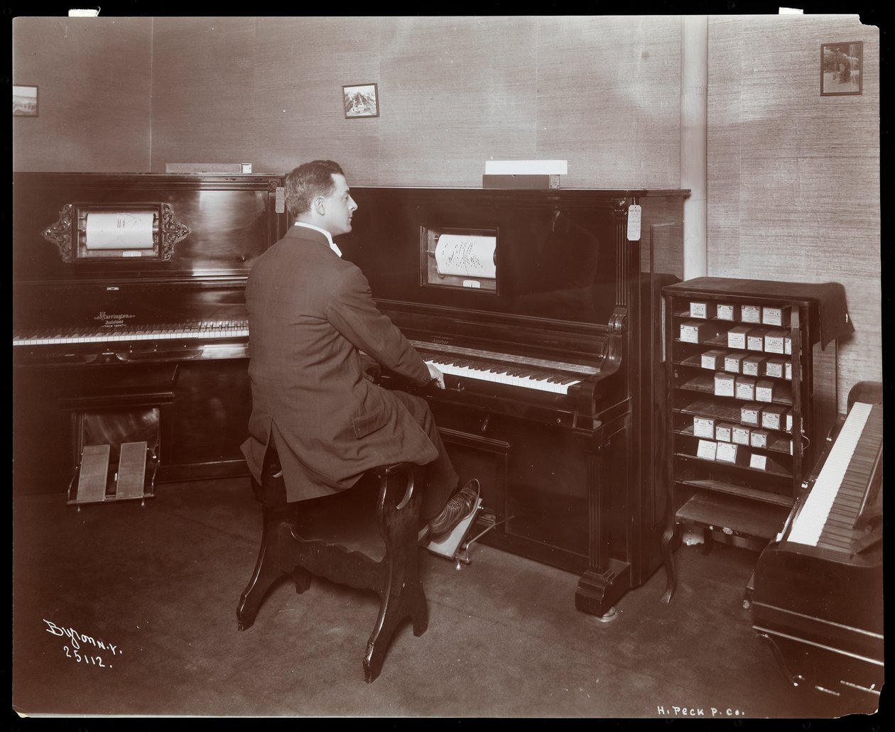 Muž hrající na klavír v showroomu pian v New Yorku, 1907 (stříbrný želatinový potisk) od Byron Company