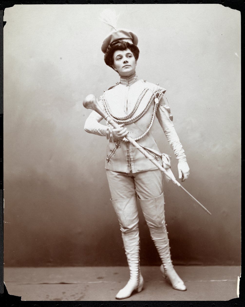 Žena v kapelnické uniformě s taktovkou v ruce, cca 1898 (stříbrný želatinový tisk) od Byron Company