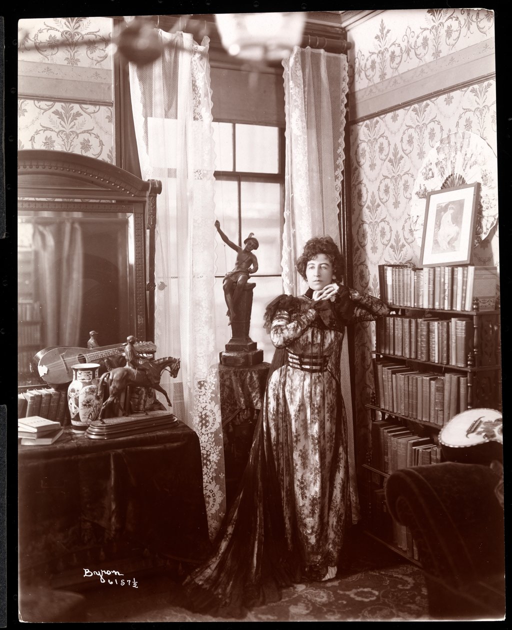 Anita Chartres stojící v rohu místnosti, kolem roku 1898 (stříbrný želatinový tisk) od Byron Company