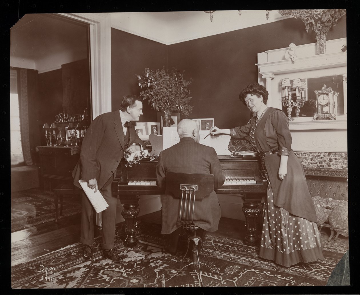 Clara De Regandová ukazuje na partituru, zatímco muž hraje na klavír, 1910 (stříbrný želatinový tisk) od Byron Company