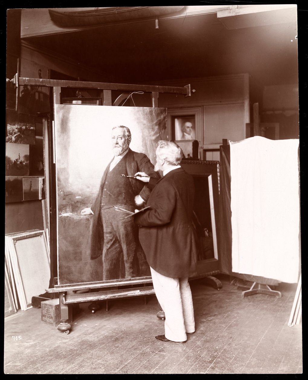 Eastman Johnson se štětcem v ruce, pracuje na portrétu prezidenta Harrisona ve svém studiu, New York, 1895 (stříbrný želatinový tisk) od Byron Company