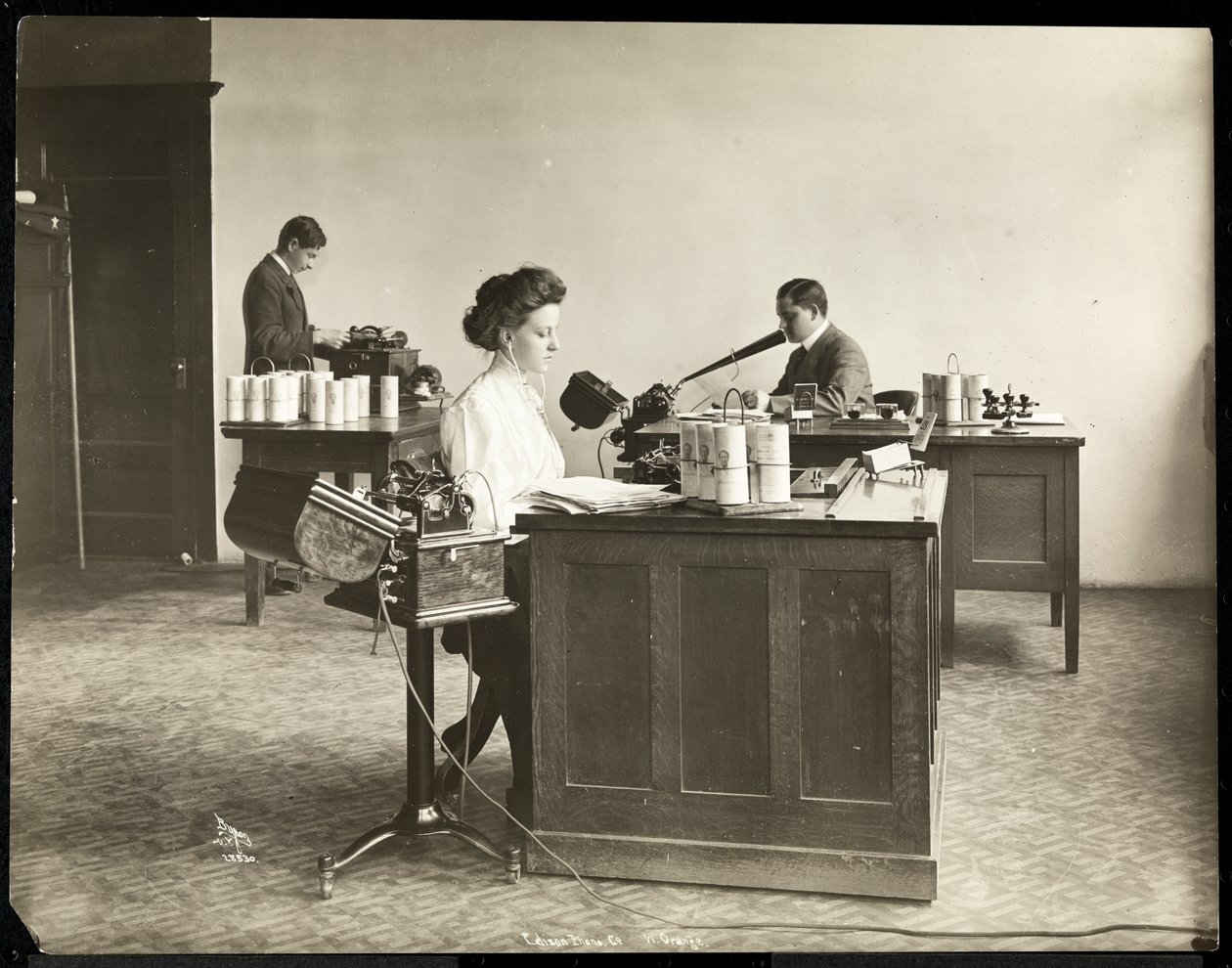 Vnitřní pohled na ženu píšící na diktafonu a muže diktujícího do druhého v Edison Phonograph Co., West Orange, New Jersey, 1903 (tisk ze stříbrné želatiny) od Byron Company