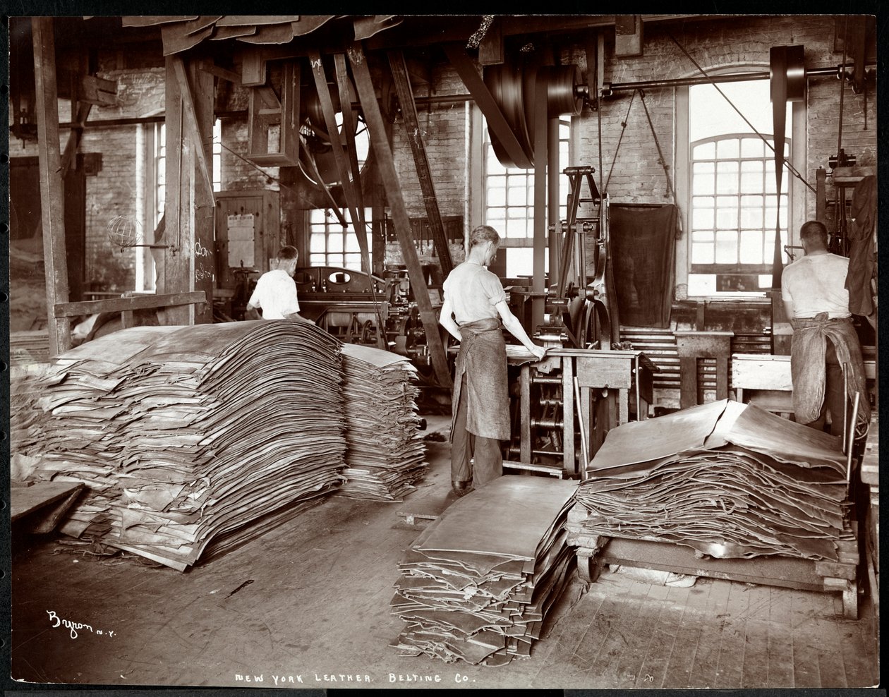 Pohled do interiéru na tři muže pracující s kůží a těžkým vybavením v New York Leather Belting Co., New York, 1905 (stříbrný želatinový tisk) od Byron Company