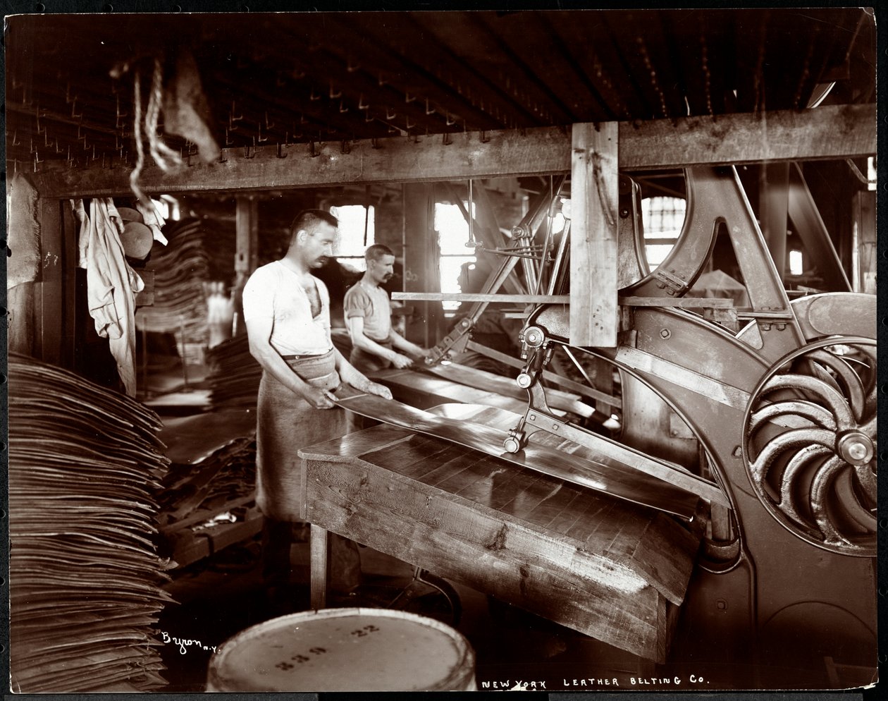 Pohled do interiéru na dva muže pracující s kůží a těžkým vybavením v New York Leather Belting Co., New York, 1905 (stříbrný želatinový tisk) od Byron Company