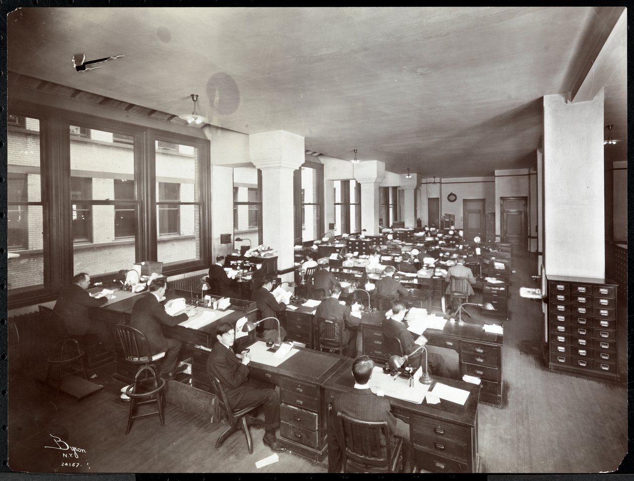 Muži a jedna žena pracují u stolů v kanceláři Metropolitan Life Insurance Co. na 23. ulici a Madison Avenue, New York, 1907 (stříbrný želatinový tisk) od Byron Company