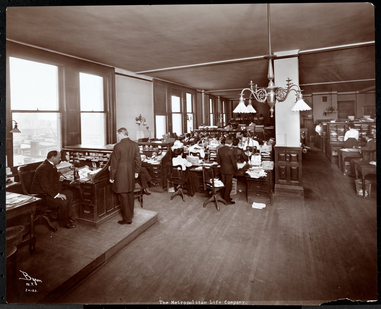 Muži a ženy pracující u stolů v kanceláři Metropolitan Life Insurance Co. na 23. ulici a Madison Avenue, New York, 1907 (potisk stříbrnou želatinou) od Byron Company