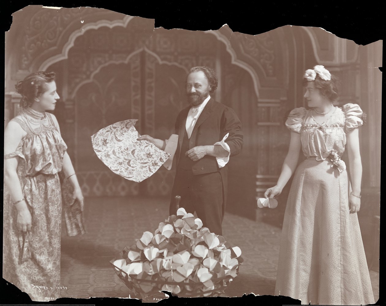 Profesor De Kolta na pódiu se dvěma ženami, 1902 (stříbrný želatinový tisk) od Byron Company