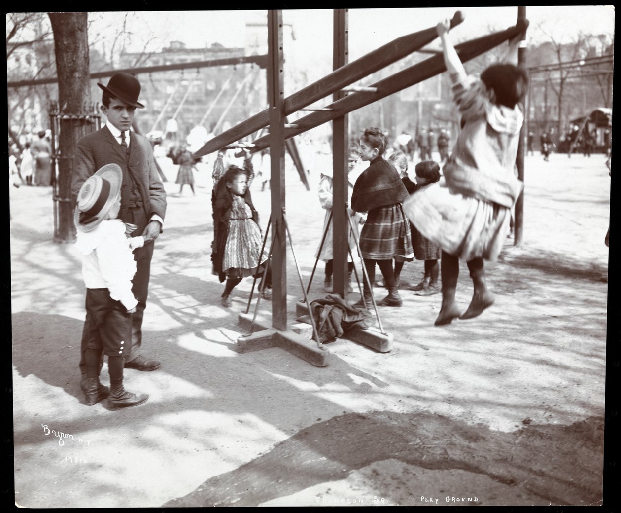 Pohled na muže dohlížejícího na děti hrající si na vybavení hřiště v Tompkins Square Park, na Arbor Day, New York, 1904 (stříbrný želatinový tisk) od Byron Company