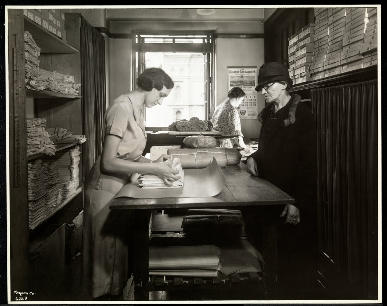 Mladá žena balí látkové materiály pro pracovníka v domácnosti, který si vezme s sebou, v New York Association for the Blind, 111 East 59th Street, New York, 1931 (potisk stříbrnou želatinou) od Byron Company