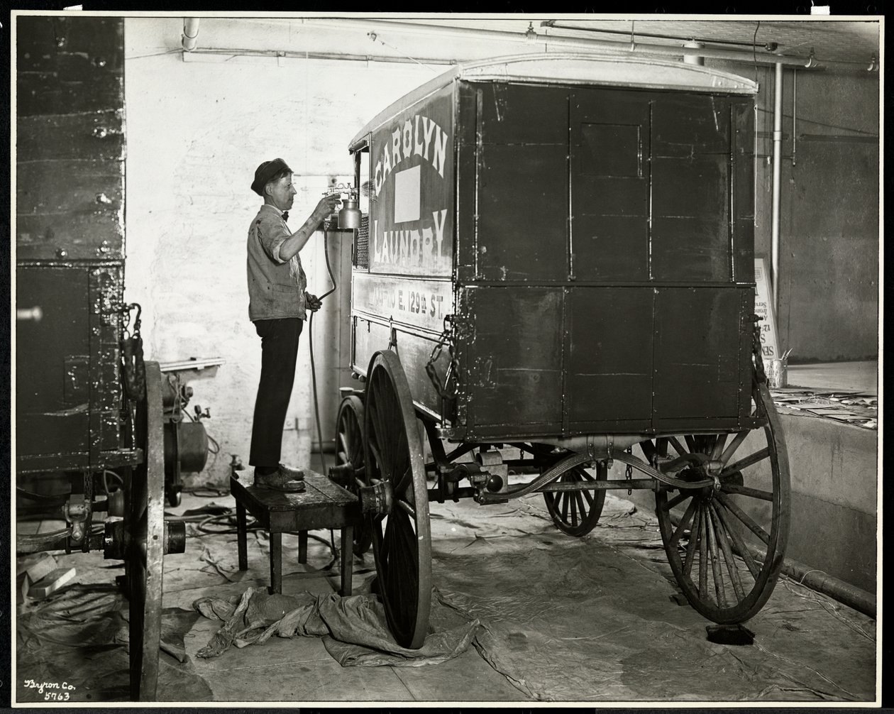 Muž, který maluje sprejem na dodávkový vůz Carolyn Laundry na 111 East 128th Street, East Harlem, New York, 1929 (stříbrný želatinový tisk) od Byron Company