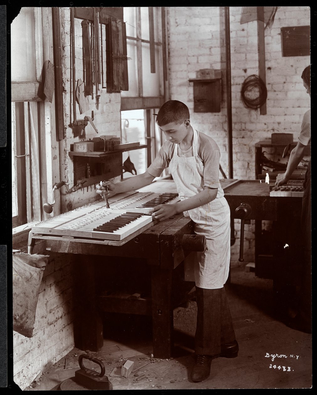 Mladý muž pracující v továrně Harrington Piano Co., 1907 (stříbrný želatinový tisk) od Byron Company