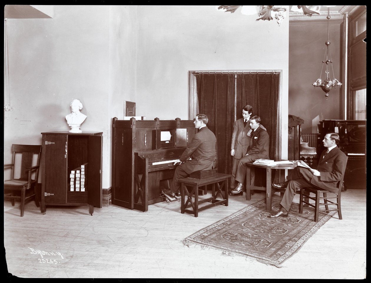 Čtyři muži, jeden hraje na klavír H. Bruman Co., 1907 (stříbrný želatinový tisk) od Byron Company