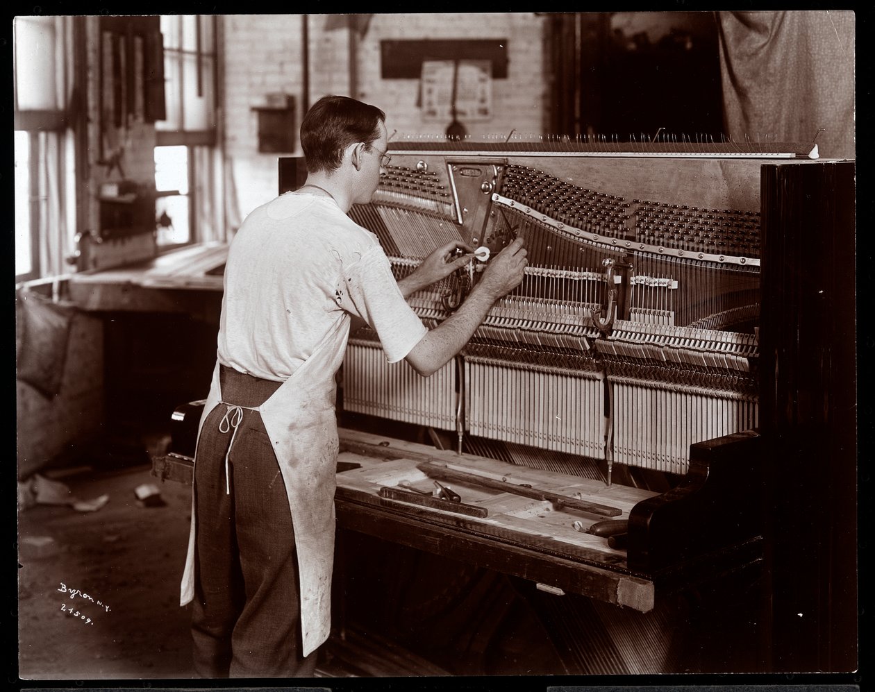 Muž pracující v továrně na klavír Hardman, Peck und Co., New York, 1907 (stříbrný želatinový tisk) od Byron Company