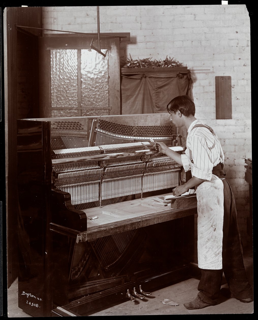 Muž pracující v továrně na klavír Hardman, Peck und Co., New York, 1907 (stříbrný želatinový tisk) od Byron Company