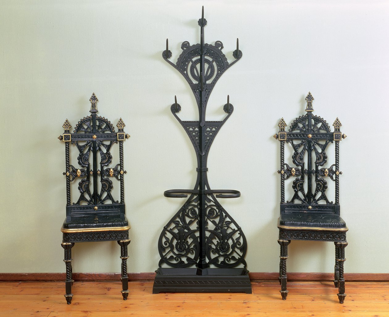 Stojan na kabáty, klobouky a deštníky lemovaný dvěma zahradními nebo předsíňovými židlemi, Coalbrookdale, 1867-69 (litina) od Christopher Dresser