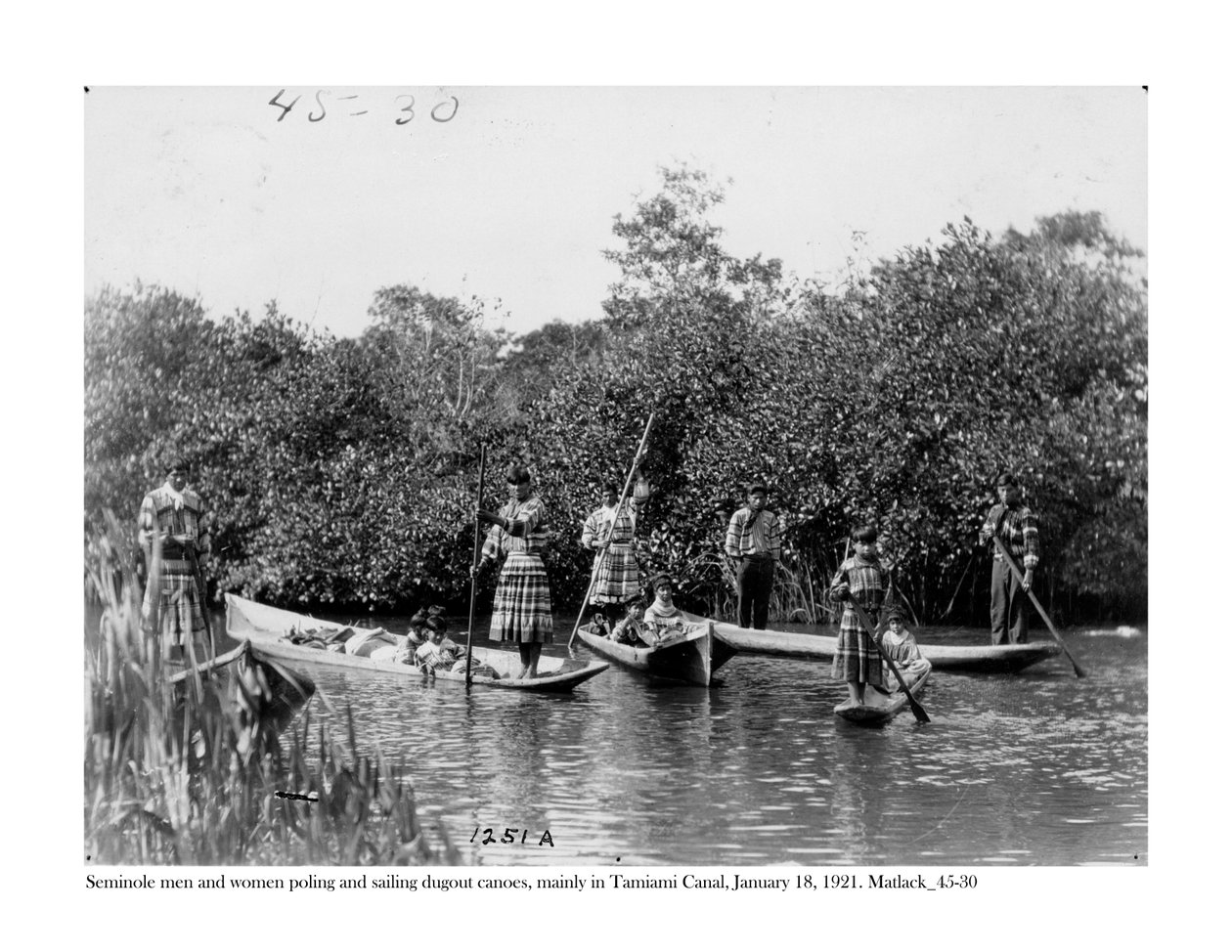 Muži a ženy Seminole hází na pól a plují vydlabané kánoe na kanálu Tamiami, 18. ledna 1921 od Claude C. Matlack