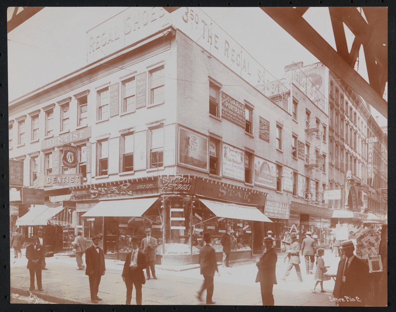 Jihozápadní roh 14th Street a 3rd Avenue zobrazující obchod Star Candies, zubaře, obchod Regal Shoe a Empire Film Co. s viditelnými chodci, billboardy a nosníkem zvýšené železnice 3rd Avenue, kolem roku 1905 (b/ w fotografii) od Company Byron