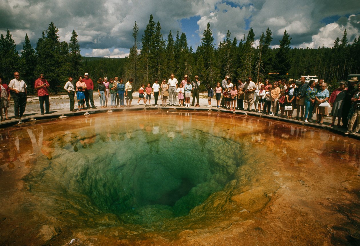 Návštěvníci parku se shromažďují kolem modrozeleného termálního bazénu ve tvaru květu. Yellowstonská přírodní rezervace... od Dean Conger