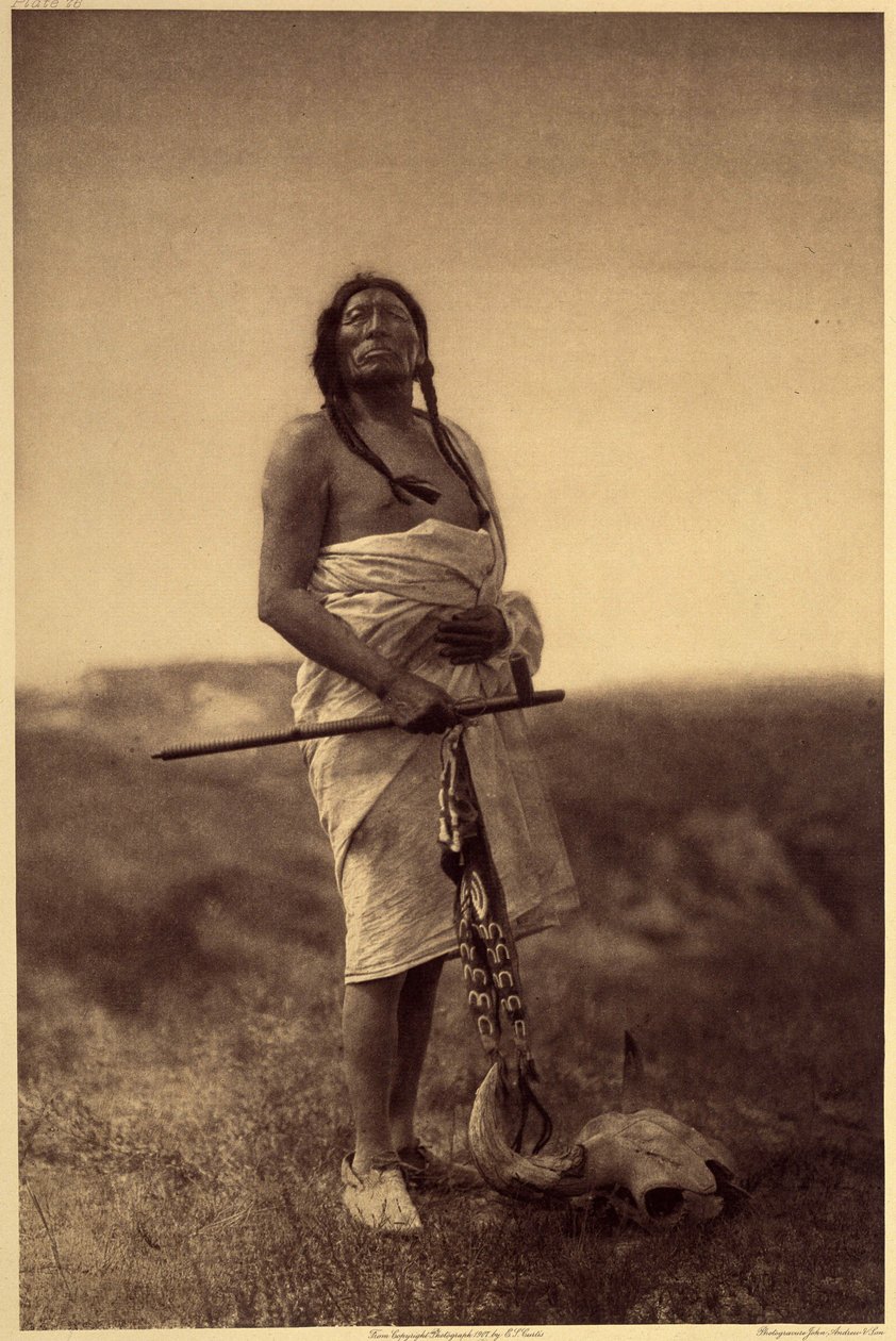 Mužský lékař. Pravděpodobně Sioux, chobotnice v ruce a buvolí lebka má nohy. Fotografie převzata ze svazku 3 encyklopedie Edwarda S. Curtise (1868-1952) o severoamerických indiánech, s předmluvou Theodora Roosevelta. V letech 1907 až 1930 bylo hospodských  od Edward Sheriff Curtis