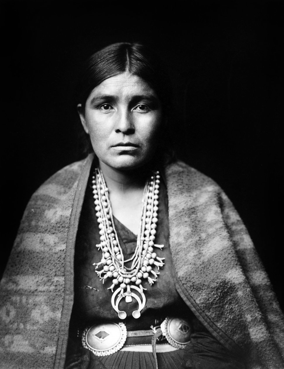 Navajo žena nosí stříbrný náhrdelník s květem tykve, pásek lastury, přikrývku přehozenou přes ramena, c. 1904, foto Edward S. Curtis od Edward Sheriff Curtis