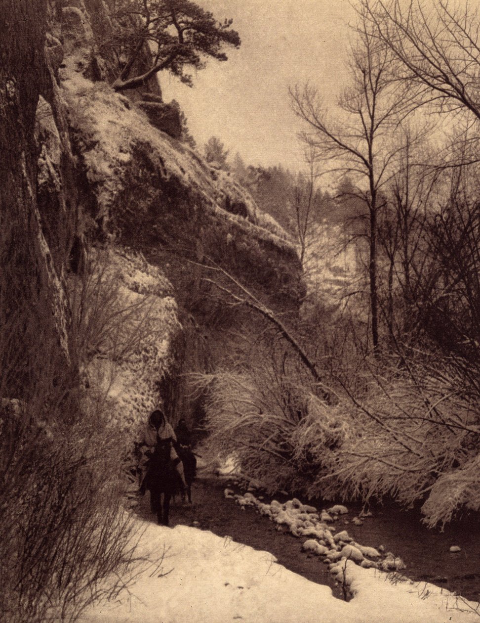 Míjení útesu, zimní scéna. Indiáni Apsaroke na koni podél útesu ve sněhu na řece Pryor v Montaně. Fotografie převzata ze svazku 4 encyklopedie vydané Edwardem S. Curtisem (1868-1952) o Indiánech Severní Ameriky, s předmluvou Theo od Edward Sheriff Curtis