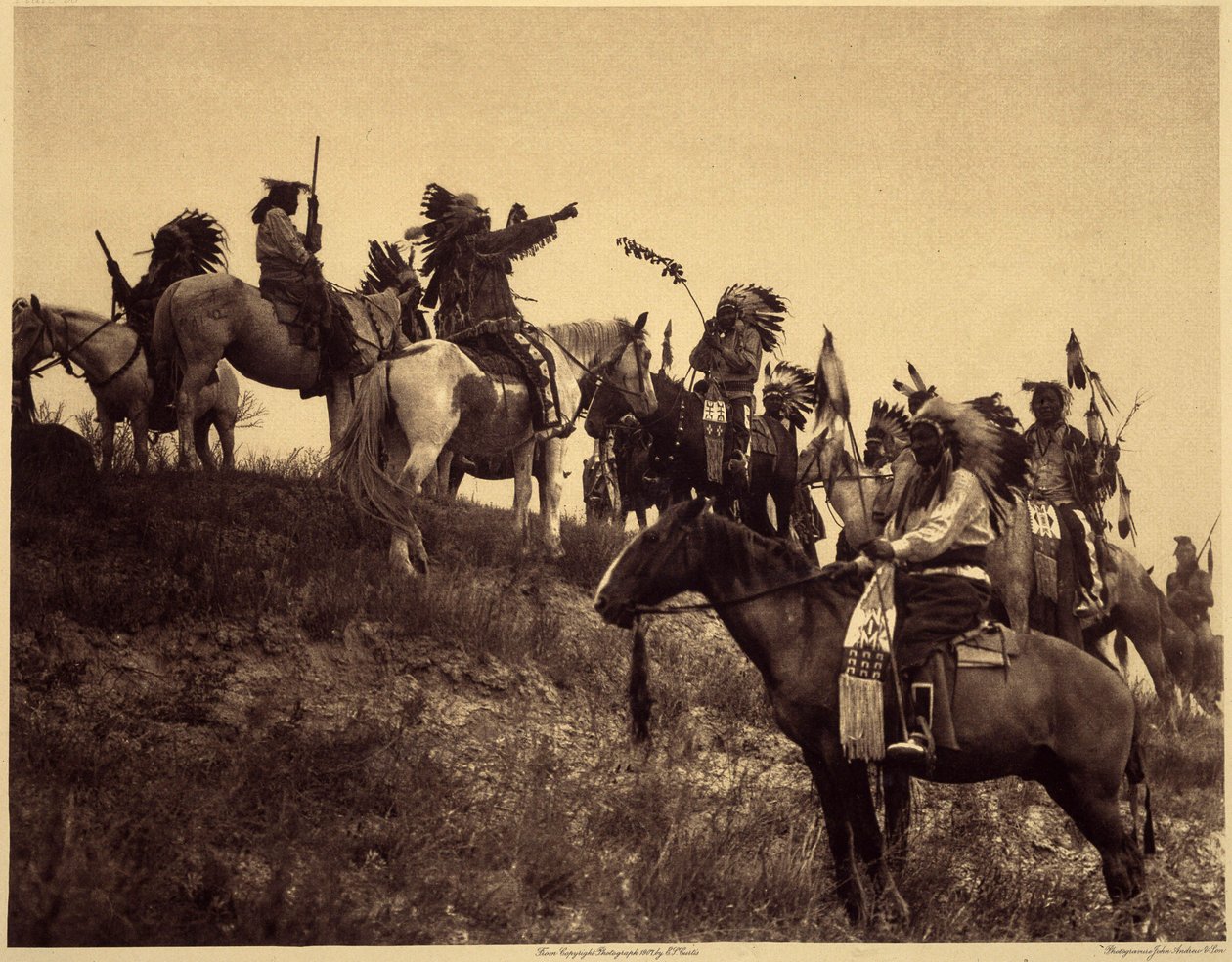 Plánování nájezdu. Indiáni se ve svých působivých typických kostýmech sdružují do mimořádně malebných skupin. Toto je jednotka ze Sioux Ogalala (Oglala), na kopci s výhledem na údolí Wounded Knee v rezervaci Pine Ridge v Jižní Dakotě. Fotografie pořízená od Edward Sheriff Curtis