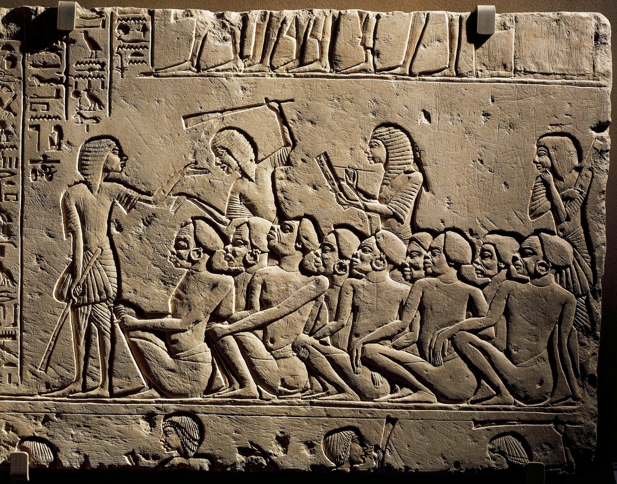 Skupina negroidních vězňů obklopená strážemi ozbrojenými holemi, zatímco písař sepisuje zprávu, reliéf z Horemhebovy hrobky v Sakkáře. od Egyptian 18th Dynasty