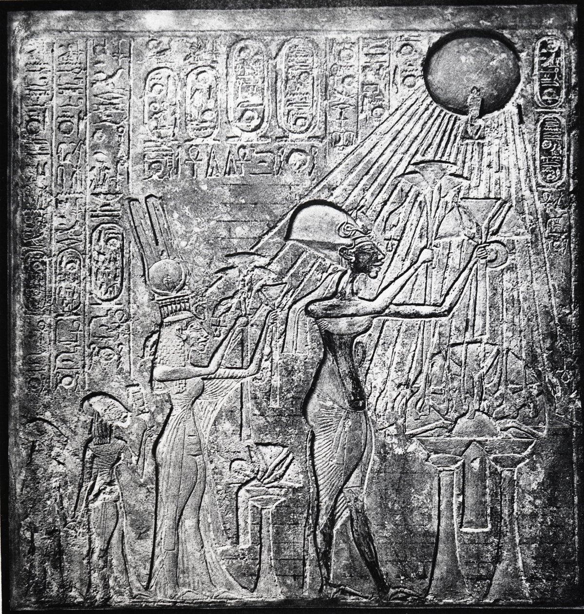 Achnaton (Amenhotep IV) kacířský faraon, vládl od roku 150 př. n. l., zde s Nefertiti a jejich dvěma dcerami nabízeli dary Slunci. Reliéf původně v Chrámu Slunce v Thébách. Lněné oděvy od Egyptian 18th Dynasty