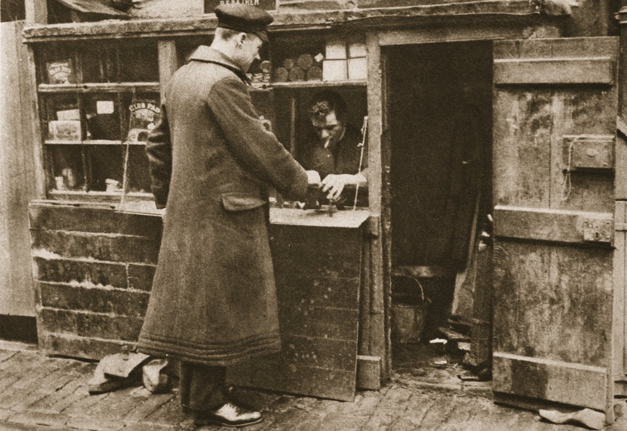 Švec, usazený v provizorní budce v dlážděném Mayfair Mews, si bere boty od šoféra z Wonderful London, vydáno 1926-27 (hlubotisk) od English Photographer