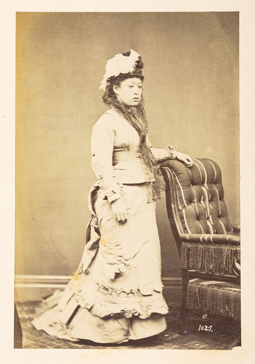 Japonka v evropských šatech, Celovečerní stojící studiový portrét mladé Japonky ve westernových šatech a klobouku,  Fotograf: Neznámý  Lucas Collection: Fotografický záznam světového turné Charlese Jamese a Mortona P, Lucase od English Photographer