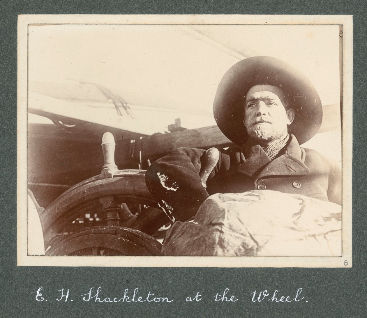 E. H. Shackleton stojí u kormidla lodi Discovery (1901) Z alba sira Ernesta Henryho Shackletona s názvem Národní antarktická expedice (1901-1903) od Ernest Henry Shackleton