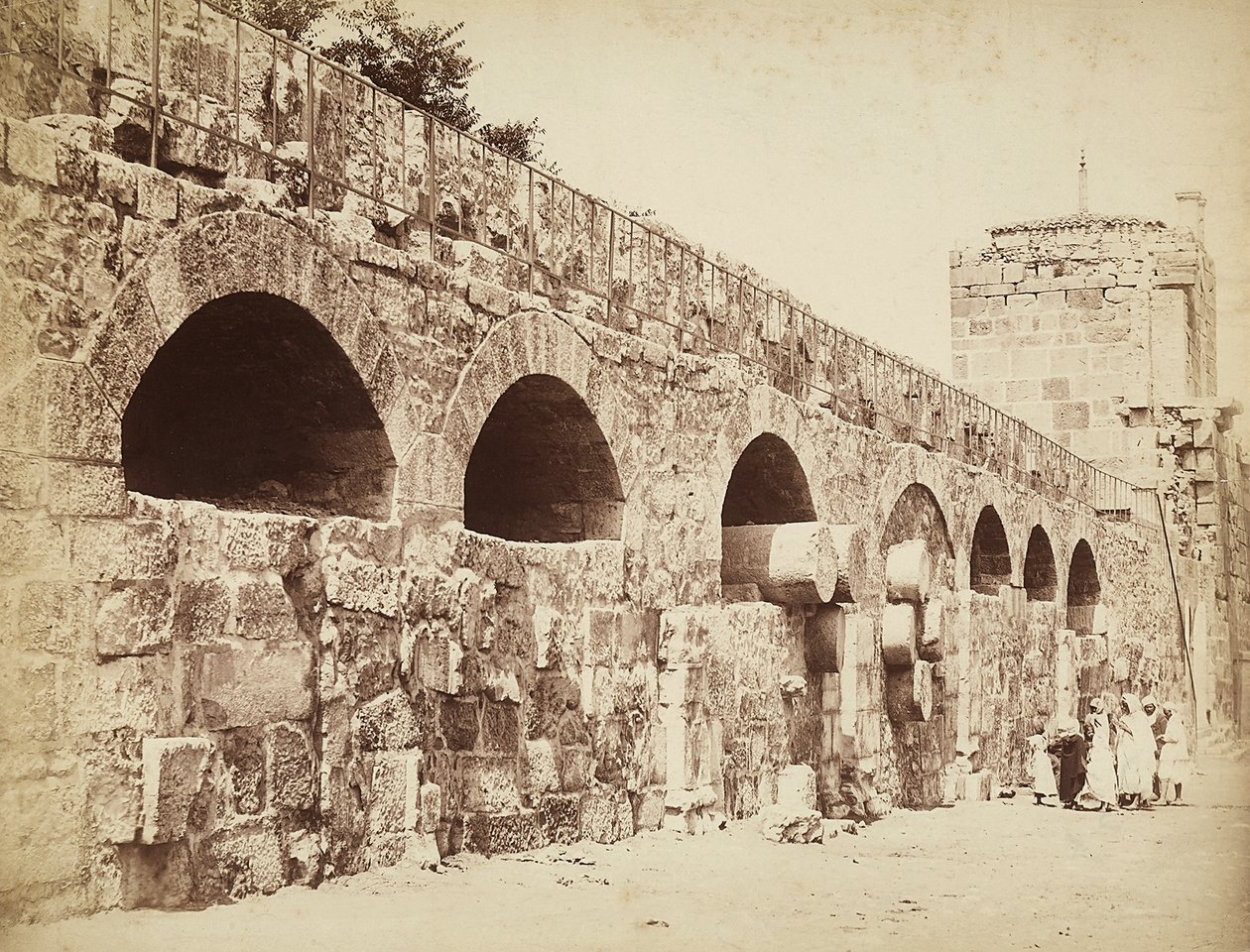 Pohled na městské hradby Heliopolis nebo Baalbek, starověké syrské město, nyní Libanon. Skupina lidí je shromážděna blízko zdi od Félix Bonfils