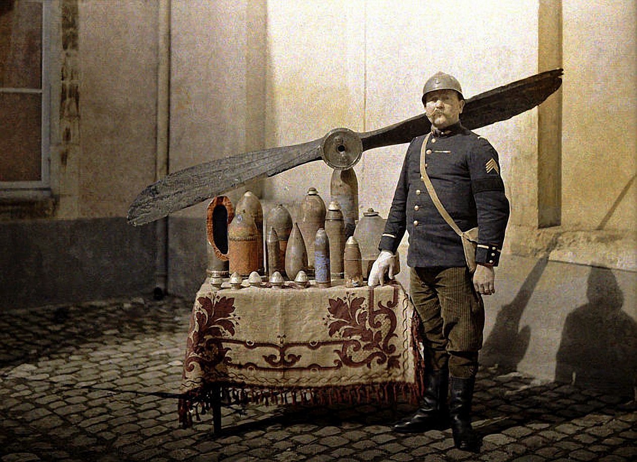 Francouzský voják u stolu s německými granáty a leteckou vrtulí, Reims, Marne, 1917 (autochrom) od Fernand Cuville