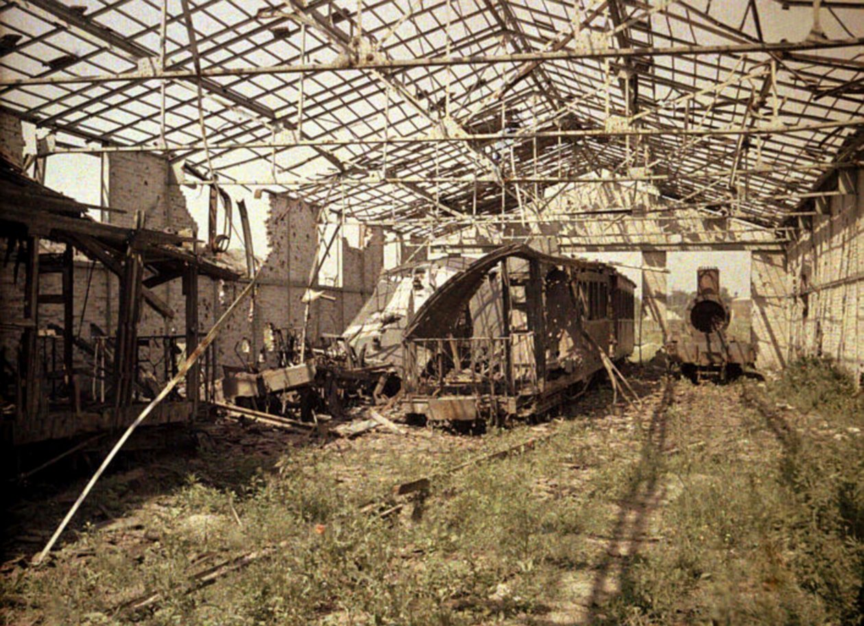 Vyhořelé nádraží a tramvajové nádraží s několika poškozenými vozidly a lokomotivou, Soissons, Aisne, Francie, 1917 (autochrom) od Fernand Cuville