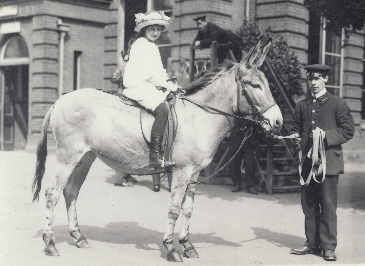 Mladá dáma jedoucí na zadku, kterou vede jeden chovatel, zatímco druhý se dívá, Londýnská zoo květen 1914 od Frederick William Bond