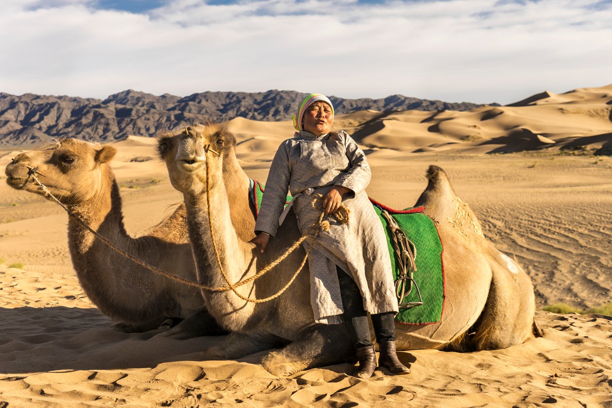 Žena odpočívá s velbloudy v poušti Jižní Gobi, Mongolsko., 2015 (foto) od Ira Block