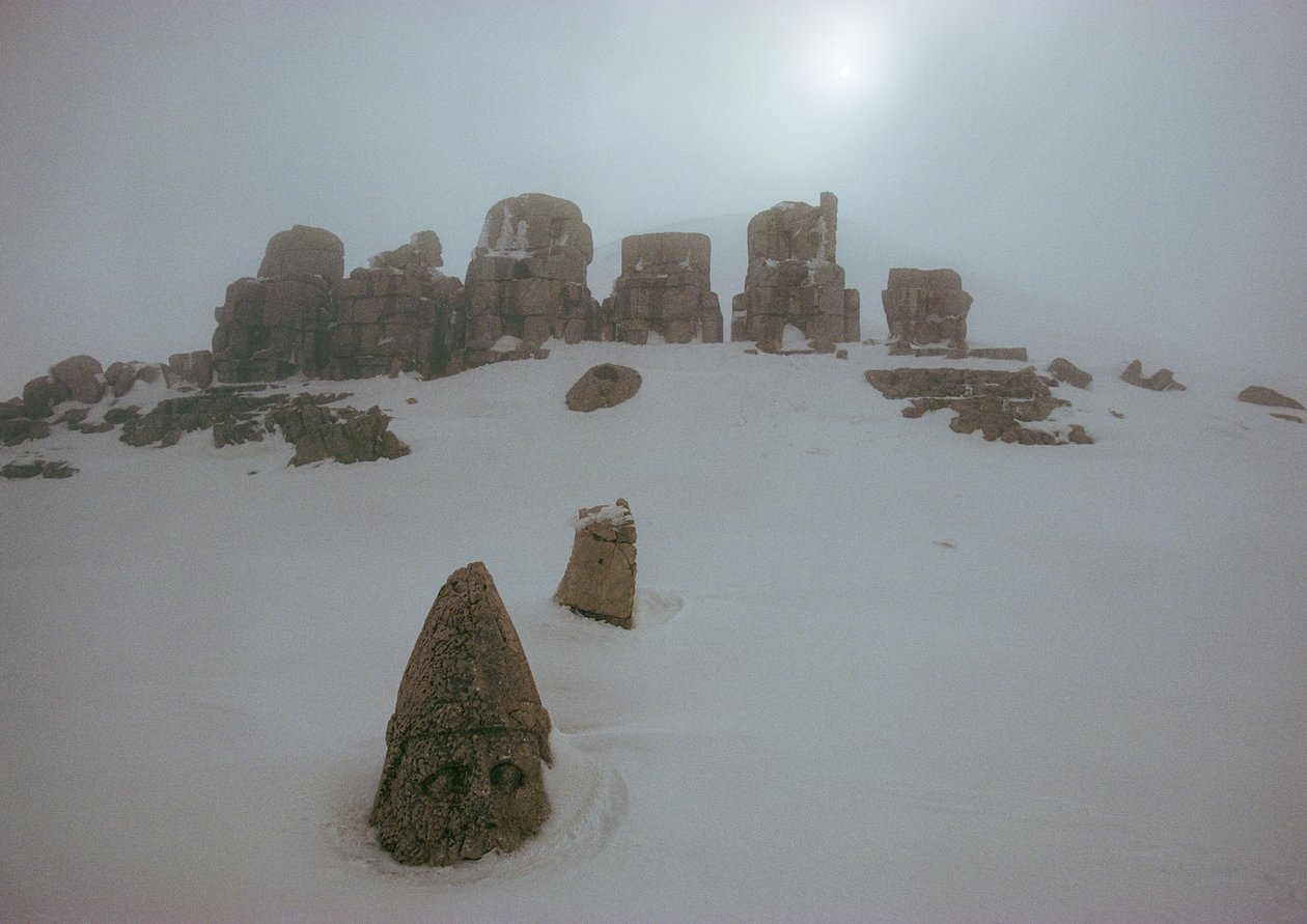 Socha boha shlíží nad sněhovou pokrývkou v Nemrud Daghu. Nemrud Dagh, Turecko. od James L Stanfield