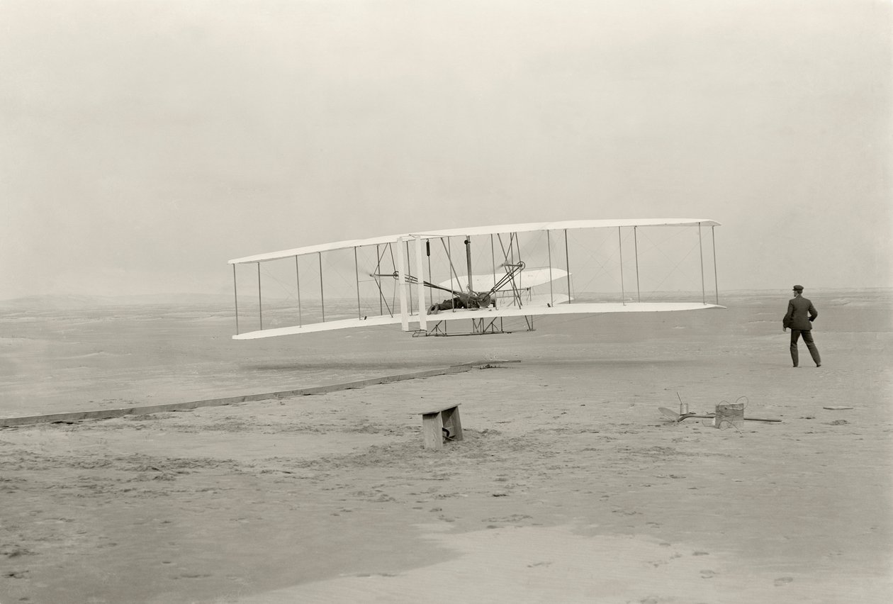 Wright Flyer I uskutečnil svůj první let z výšky 120 stop za 12 sekund v Kitty Hawk v Severní Karolíně. od John T. Daniels