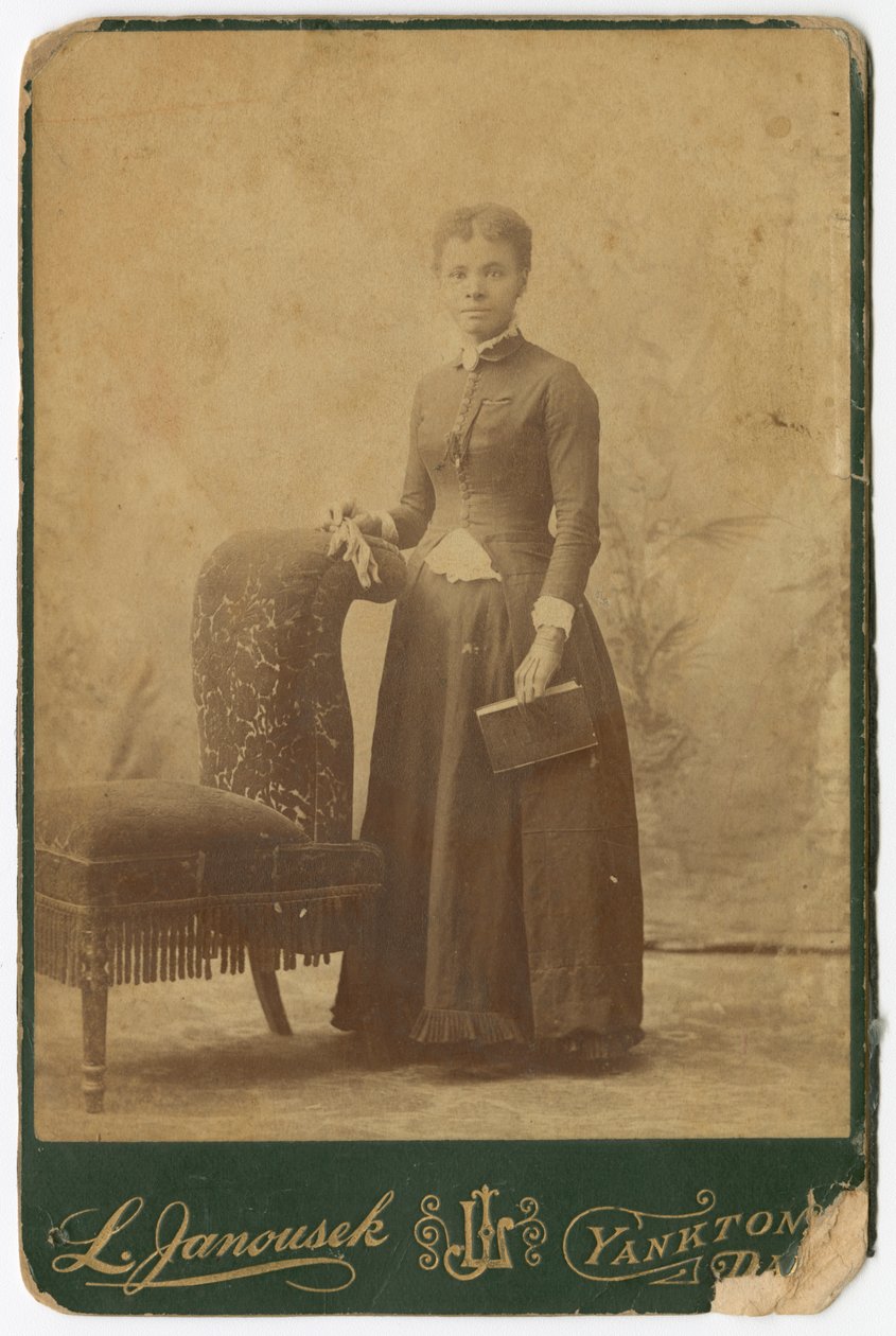 Fotografie ženy stojící vedle židle a držící knihu, konec 19. století. od Louis Janousek