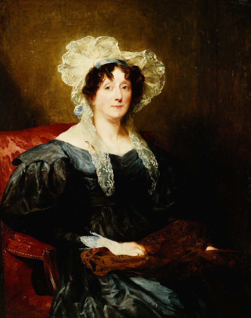 Portrét dámy, sedící na půl délky, v tmavě modrých šatech a bílé krajkové čepici s modrou mašlí, držící vyšívání, od Margaret Sarah Carpenter