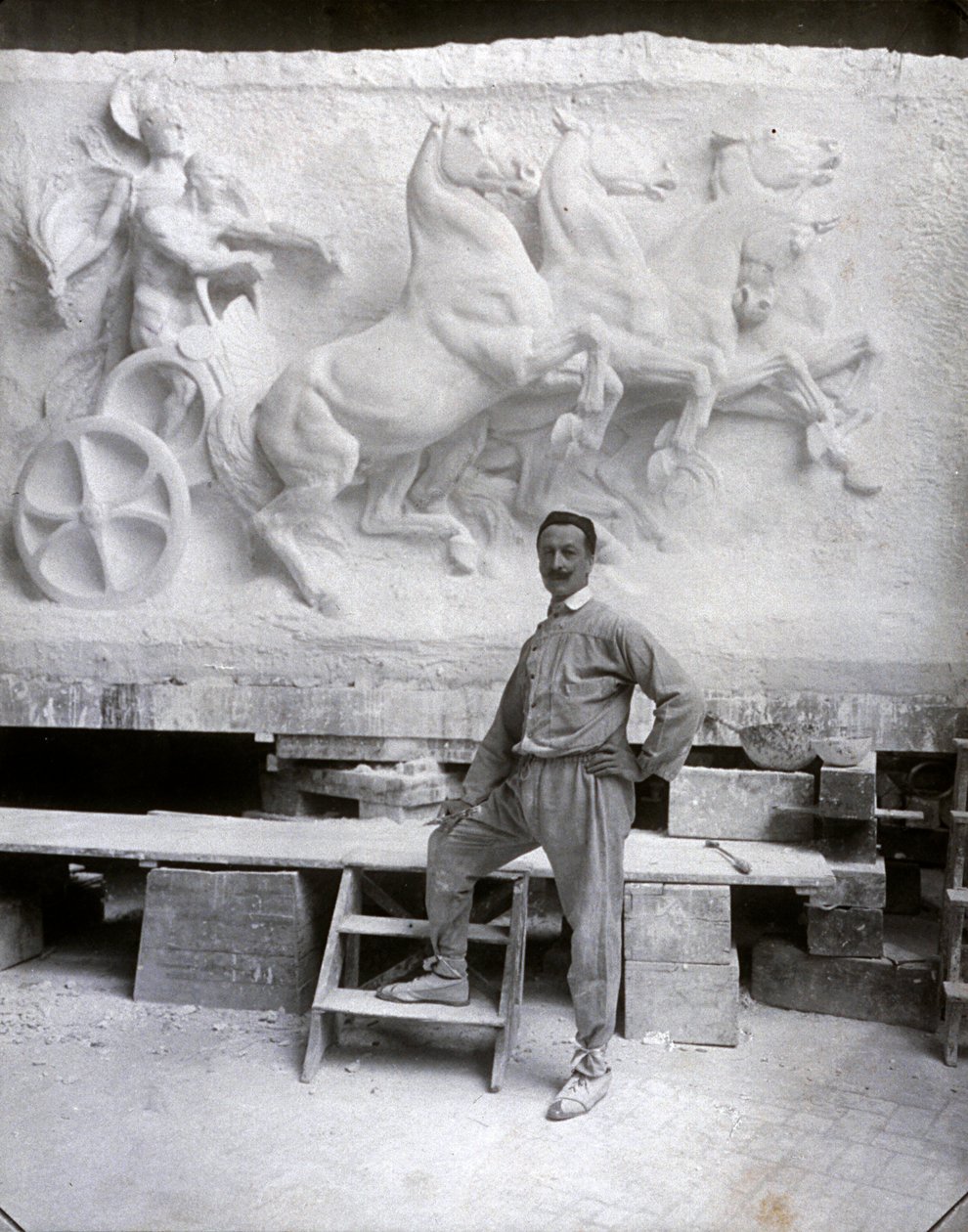 Celovečerní portrét slavného sochaře Pietra Canonica. Pózuje ve svém ateliéru před mramorovým vysokým reliéfem, na kterém pracuje (černobílá fotografie) od Mario Nunes Vais