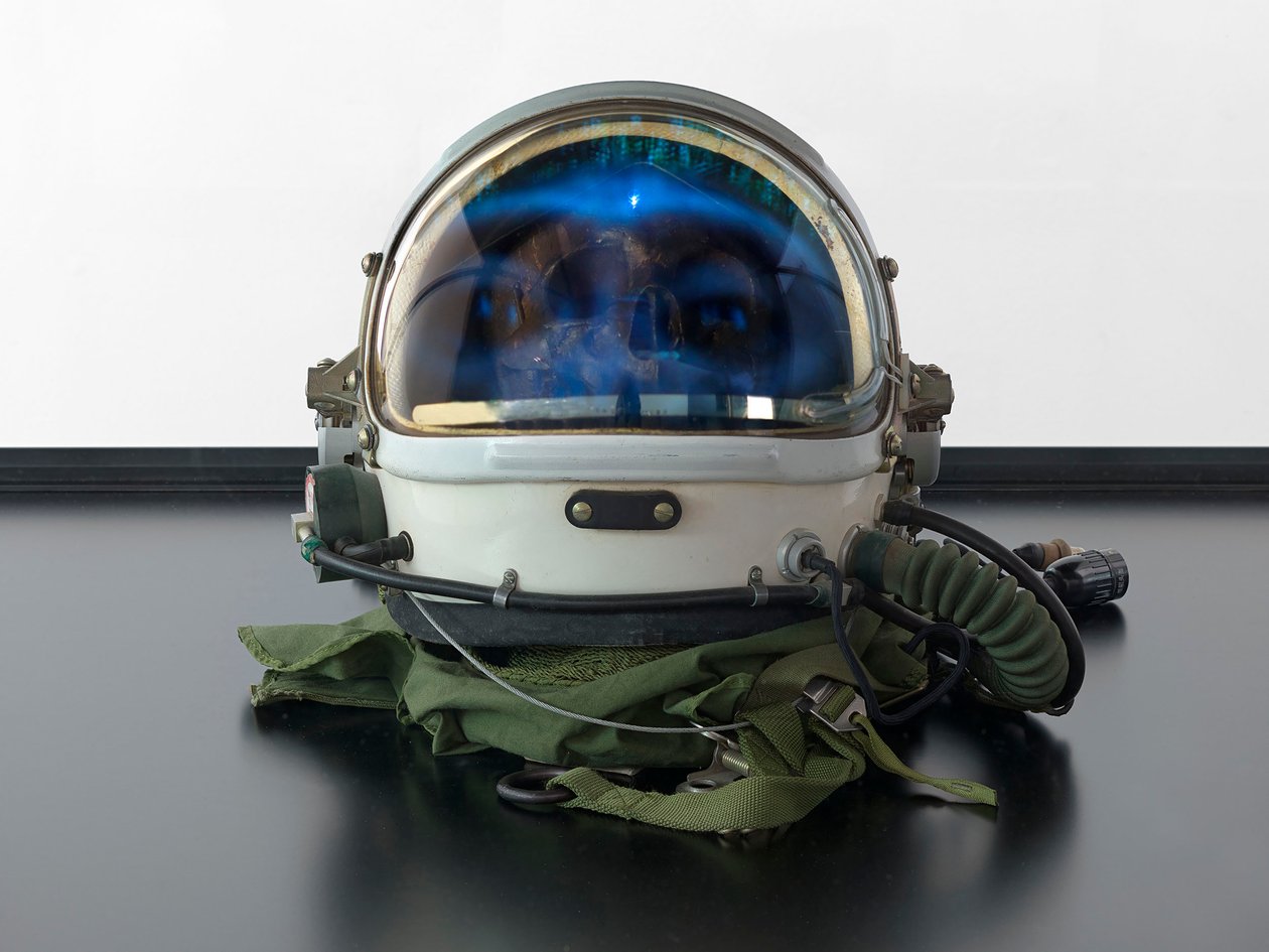 Alpha Omega, 2016 (sklo, LCD displej, přehrávač médií, replika lebky, vesmírná helma, dřevo) od Mat Collishaw