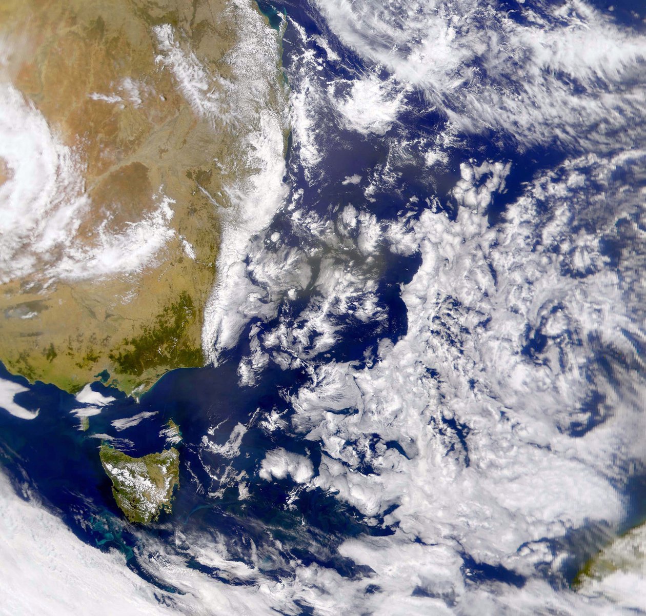 Satelitní fotografie Tasmanova moře částečně zakrytého mrakem. Vlevo je část Austrálie s Tasmánií pod ní. NASA. Věda od National Aeronautics and Space Administration National Aeronautics and Space Administration