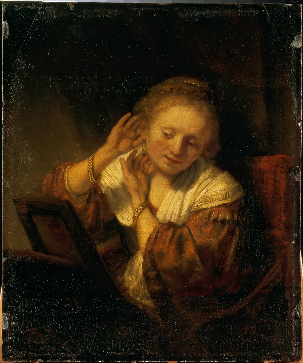 Mladá žena, která se zdobí náušnicemi od Rembrandt van Rijn